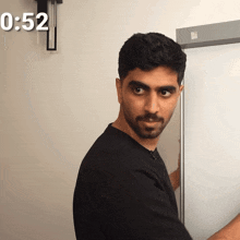 a man in a black shirt stands in front of a white board with the time 1:52
