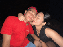 a man in a red collared shirt is kissing a woman on the cheek
