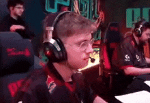 a man wearing headphones and glasses is playing a video game on a computer .