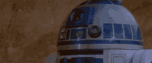 r2d2 is laying on the ground next to a large rock .