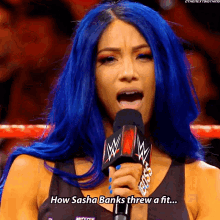 a woman with blue hair is holding a microphone and says " how sasha banks threw a fit "