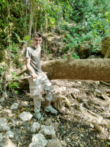 a man leaning on a tree trunk with a stick
