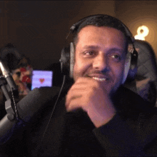 a man wearing headphones is sitting in front of a microphone and smiling