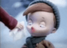 a close up of a cartoon character with a red nose being held by a person .