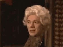 a man in a wig is peeking out from behind a door .