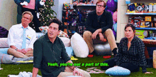 a group of people are sitting on the grass in a store and one of them is saying yeah you 're not part of this .