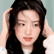 a close up of a woman 's face with her hands on her hair