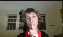 a young man is making a shhh gesture with his finger to his lips .