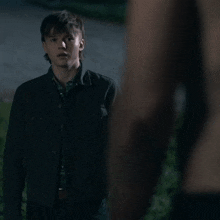 a man without a shirt is standing next to a young boy in a black jacket