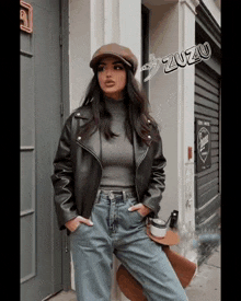 a woman wearing a black leather jacket and a hat is standing in front of a building