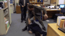 a man in a suit and tie is fighting another man on the floor .