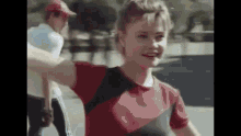 a young girl in a red shirt is smiling and holding a man 's hand .