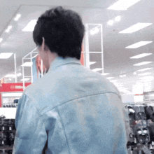 a man in a denim jacket stands in a store