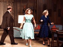 a woman in a blue dress is walking in a living room