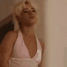 a woman in a pink bikini top is standing in front of a mirror and looking at the camera .