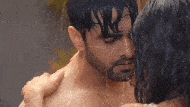 a man and a woman are kissing in the rain and water is dripping from their faces .