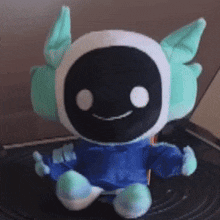 a stuffed animal wearing headphones and a blue shirt is sitting on a black surface