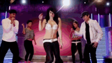 a group of people are dancing on a stage and one of them is wearing a white jacket with the letter a on it