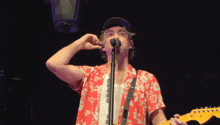 a man singing into a microphone while holding a guitar in his hand