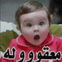 a baby in a pink jacket is making a surprised face with his mouth open .