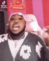 a man in a pink hat is making a funny face while sitting in a chair .