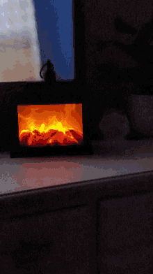 a fire burning in a dark room with a blue sky behind it
