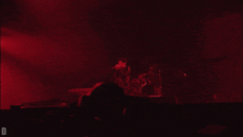 a man in a leather jacket is kneeling down in a red light with the letter d in the corner