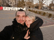 a man and a woman are posing for a picture in front of a sign that says berdashck