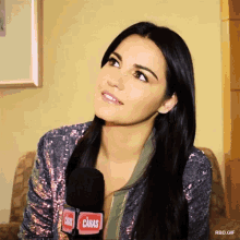a woman is sitting in front of a microphone that says caras on it