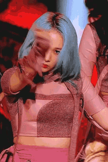 a girl with blue hair is wearing a pink top and gloves while dancing on a stage .
