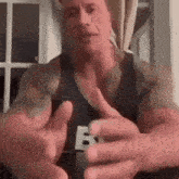 a muscular man is giving a thumbs up sign while wearing a black tank top .