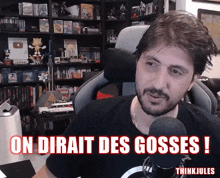 a man sitting in front of a microphone with the words " on dirait des gosses " written in red