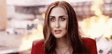 a woman in a red jacket is standing in front of a fire in a city .