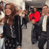 a group of people are dancing in a hallway and one of them is wearing a red nike jacket