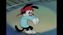 a cartoon dog wearing a red hat and a blue sweater is standing on a stage .