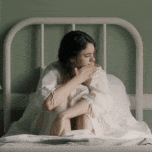 a woman in a white dress is sitting in a bed
