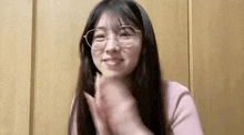 a woman wearing glasses is clapping her hands and smiling .