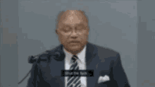 a man in a suit and tie stands in front of a microphone .