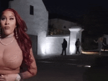 a woman with red hair is standing in front of a white building .