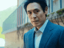 a man in a blue suit and white shirt is standing in front of a building