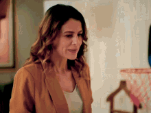 a woman wearing a brown jacket and a white shirt is smiling