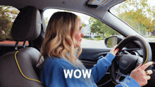 a woman is driving a car and the word wow is on the bottom right
