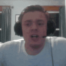 a man wearing headphones and a microphone is looking at the camera and making a funny face .