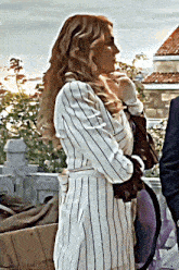 a woman in a striped jacket is holding a baby in her arms