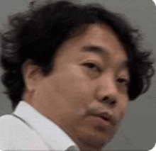 a man with curly hair is wearing a white shirt and tie and making a funny face .