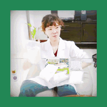 a woman in a lab coat is sitting at a table with a bottle of purple liquid in front of her