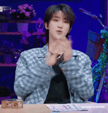a man in a checkered jacket is clapping his hands in front of a table