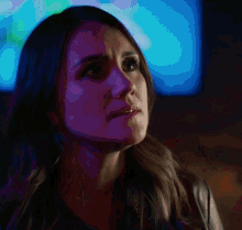 a close up of a woman 's face with purple lights in the background