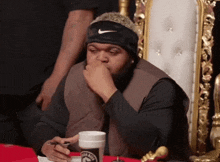 a man wearing a nike headband is sitting at a table with a cup of coffee