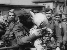 a black and white photo of a man kissing a child while holding a bouquet of flowers .